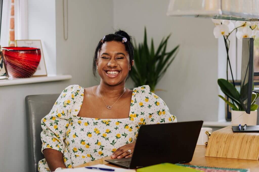 Chanelle smiling while working on her laptop
